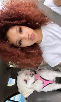 a woman with curly hair sitting next to a white dog