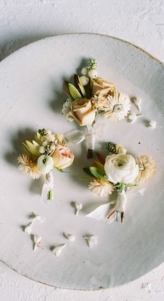 three flowers are placed on a plate with white petals and leaves in the center, along with other flowers