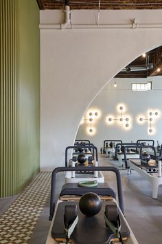 an indoor gym with rows of exercise equipment and lights on the wall behind them,