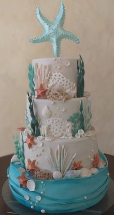 a three tiered cake decorated with sea shells and starfish