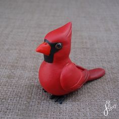 a red toy bird sitting on the ground