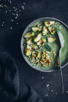 a bowl filled with green smoothie and topped with pistachio sprouts