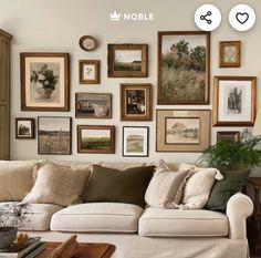 a living room filled with lots of framed pictures on the wall above a white couch