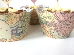 two cupcakes with maps on them are sitting next to each other in paper cups