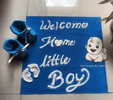 a welcome home mat with baby feet and shoes on the floor next to it that says,'welcome home little boy '