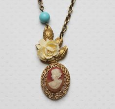 "Vintage Cameo Necklace Flower Gold Leaf Necklace Vintage Jewelry One of a Kind From my Vintage Garden Collection, this charming vintage Cameo pendant sits below a spray of aged brass leaves on which is staged a cream colored vintage lucite flower strung below a beautiful turquoise blue Czech glass bead. Hangs on a brass cable chain. Length shown is 26\" can be adjusted to a different length . The Cameo is 1.75\" x 3\" . H A N D M A D E * We hand make all pieces in our Water Mill New York studio Vintage Cream Flower Jewelry, Vintage Handmade Beige Jewelry, Vintage Beige Necklace For Gift, Vintage Beige Necklace For Gifts, Vintage Beige Necklace Gift, Vintage Handmade Cream Jewelry, Gold Leaf Necklace, Water Mill, Necklace Flower