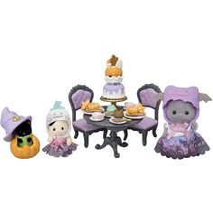 three small figurines sitting around a table with cakes on it and other decorations