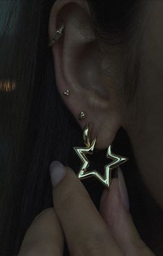 a close up of a person's ear with a pair of earrings in the shape of stars