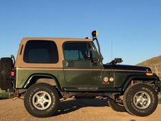 a green jeep parked on top of a dirt road