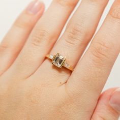 a woman's hand with an engagement ring on top of her finger, showing the center stone