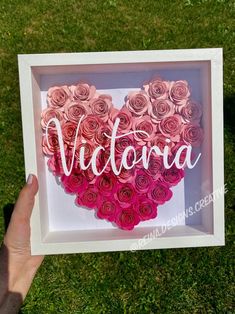 someone is holding up a heart made out of paper roses with the word victoria in it