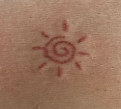 the back of a person's neck with a sun tattoo on it and red ink