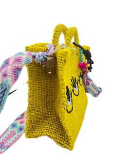 a small yellow bag with an odd face on the front and sides, hanging from a string