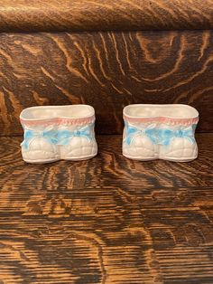 two small vases sitting next to each other on a wooden table with wood grain