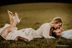 a man and woman laying in the grass with their heads touching each other's noses