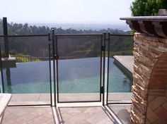 an outdoor swimming pool with fenced in area and stone fire place next to it