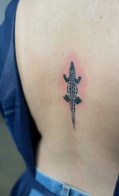 a small lizard tattoo on the back of a woman