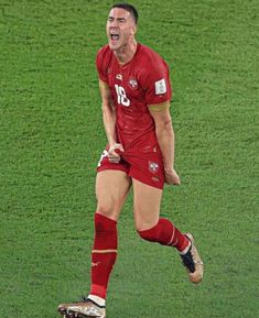 a male soccer player in red is on the field and has his mouth wide open