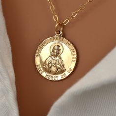 "Gold Jesus Pendant Necklace Christian Necklaces for Women. A Jesus pendant necklace made with all 14K gold filled materials. The text around the circumference reads: \"Sacred heart of Jesus have mercy on us.\" The pendant is detailed and solid, yet lightweight enough for comfortable all-day wear. The pendant measures approximately 15mm in diameter (about 5/8 inch).  What is Gold Filled? Gold filled jewelry has a layer of solid gold that is 100 times thicker than that of gold plated jewelry. It is hypoallergenic, resistant to tarnish, and will not chip or fade over time. Gold filled has an appearance nearly identical to solid gold, but with a more affordable price. It is highly durable and with proper care will last a lifetime. Browse my shop: ALLDANAE.etsy.com" Jesus Necklace, Christian Necklace, Lovely Necklace, Sacred Heart, Gold Filled Jewelry, Christian Gifts, Gold Plated Jewelry, Jewelry Plate, Gold Pendant