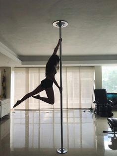 a woman standing on one leg in the middle of a pole