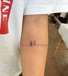 a person with a small tattoo on their arm that has two birds sitting on the line