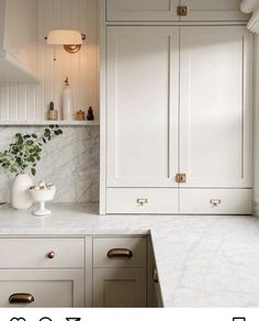 a white kitchen with marble counter tops and gold pulls on the cabinet doors is featured in this post