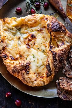 baked bread with cheese and herbs on a plate next to some other food items, along with a glass of wine