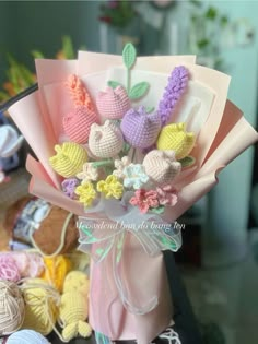 a bouquet of crocheted flowers sitting on top of a table next to balls of yarn