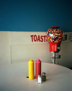 three different colored candles sitting on top of a white table