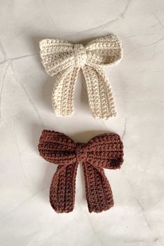 two crocheted bows are sitting next to each other on a white table top