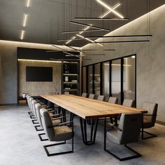 a long wooden table surrounded by chairs in a room with lights on the ceiling above it