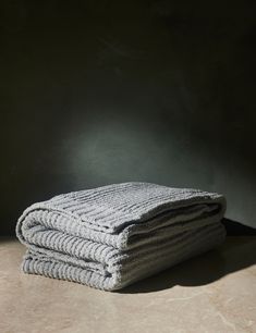 three folded towels sitting on top of each other in front of a black wall and floor