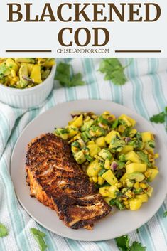 grilled chicken with mango salsa on a white plate next to a bowl of salad