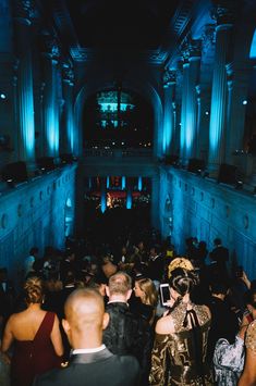 a large group of people standing in a room with blue lights on the walls and ceiling