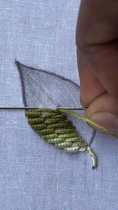 the needle is being used to sew an embroidered leaf