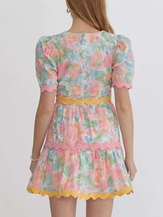 Introducing our Ric Rac Trim Floral Mini Dress – a burst of playful elegance for your wardrobe. This charming mini dress features a delightful watercolor floral print in pastel hues of pink, green, and blue. The dress is beautifully detailed with scalloped trim along the neckline, sleeves, and hem, adding a whimsical touch. The flattering silhouette is enhanced with puff sleeves and a tiered skirt that creates a flirty, feminine shape. The dress is fully lined for comfort and has a hidden back z Spring Brunch Dresses With Scalloped Edges, Spring Brunch Dress With Scalloped Edges, Feminine Scalloped Edge Dresses For Garden Party, Feminine Dresses With Scalloped Edges For Garden Party, Multicolor Short Sleeve Mini Dress For Garden Party, Pastel Ruffled Dresses For Spring, Cute Summer Dresses With Scalloped Edges, Pastel Fitted Mini Dress, Fitted Pastel Mini Dress