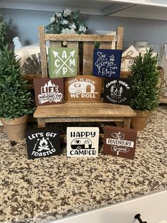 some wooden signs sitting on top of a counter next to potted plants and trees