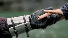 a person holding the hand of another person wearing leather gloves with metal straps on them