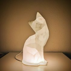 a white cat shaped lamp sitting on top of a table next to a brown wall