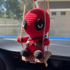 a crocheted stuffed animal hanging from the dashboard of a car in front of a window