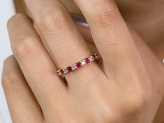 a woman's hand with a pink and white diamond ring on her left finger