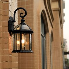 an old fashioned light hanging on the side of a building next to a brick wall