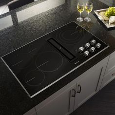 a glass of wine is sitting on the counter top next to an electric cooktop