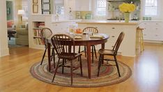 a dining room table with four chairs and a rug on the floor in front of it