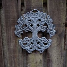 a metal cross on a wooden fence with knots in the shape of a tree ornament