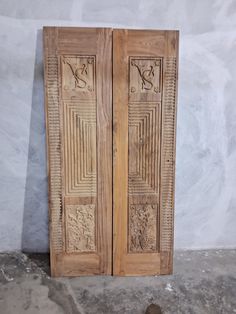 two wooden doors sitting next to each other on the ground in front of a wall