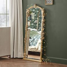 a large gold mirror sitting on top of a wooden floor next to a white bed