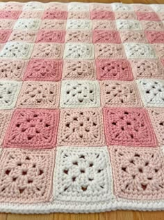 a pink and white crocheted blanket sitting on top of a wooden floor