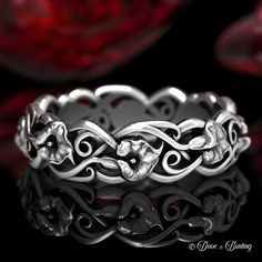 a silver ring with flowers and leaves on it's sides, in front of a black background