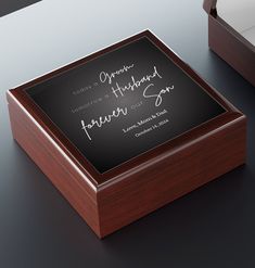 a wooden box with writing on it sitting on a table next to another box that is open